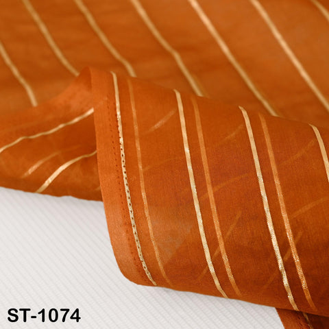 Burnt orange organza dupatta with gold vertical stripes draped over a table and hanging on a rod, highlighting its translucent fabric and shimmering design.