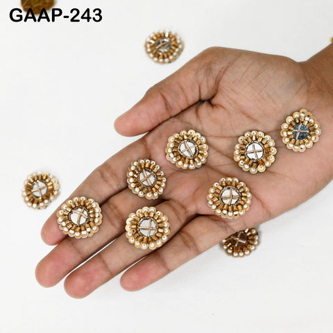 Mirror patch showing gold zari thread, mirror glass center, and beading detail in handmade embellishment set.