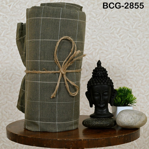 a wooden table with a rolled-up green cloth, a small black Buddha statue, a small potted plant, and a rock.