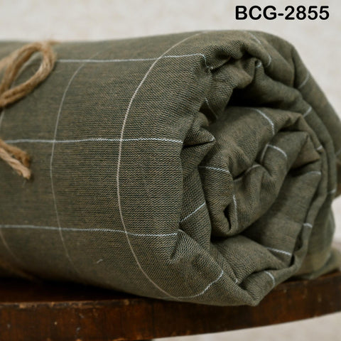 A rolled-up green and white checkered fabric is displayed on a wooden surface.
