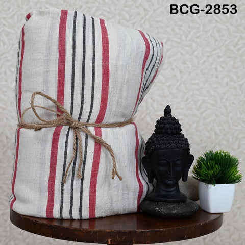 a wooden table with a large striped towel tied with a rope, a small black Buddha statue, and a potted plant.