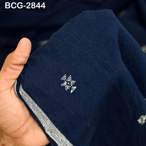A hand is holding a piece of dark blue fabric with a white patterned design on it.