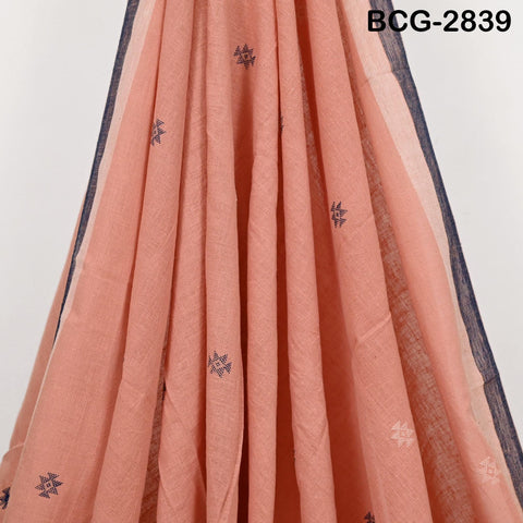 a close-up view of a peach-colored fabric with blue floral embroidered patterns.