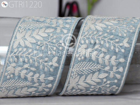 two pieces of blue fabric with white floral embroidery, arranged side by side.