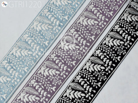 three identical spools of embroidered fabric, each with a repeating pattern of leaves and flowers in different colors.