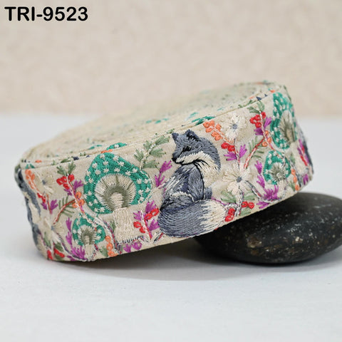 A hat with a floral pattern and a small embroidered fox on it, placed on a black rock.