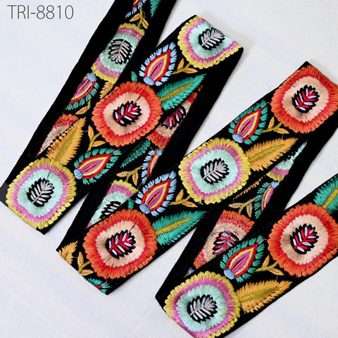 a collection of colorful, intricately embroidered fabric pieces, including a headband and a scarf, with a variety of floral and leaf designs.