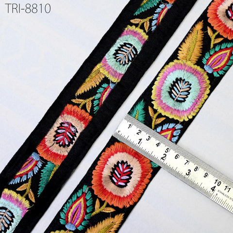 a close-up view of a decorative fabric with a floral pattern, featuring a black border and a ruler for size reference.