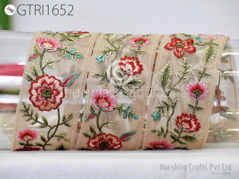a decorative beige fabric with a floral pattern, including red and pink flowers and green leaves. The fabric appears to be a decorative ribbon or textile, possibly used for embellishment or as a gift.