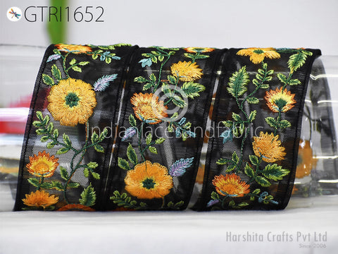 a close-up view of a decorative black ribbon adorned with vibrant yellow and orange floral embroidery.