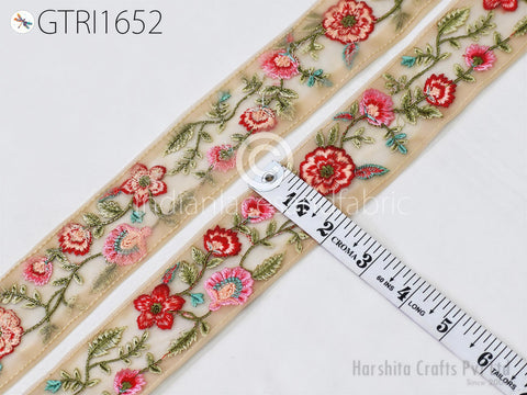 a close-up view of a decorative fabric with a floral pattern, including red and pink flowers, and green leaves. A ruler is placed next to the fabric, indicating its size.