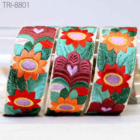 three colorful, embroidered fabric pieces with floral designs.