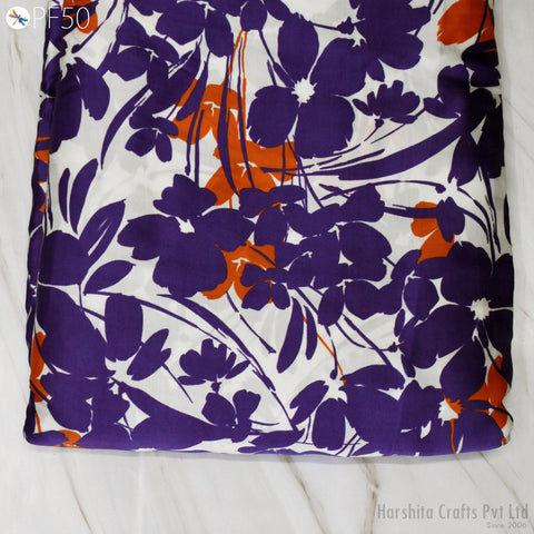 a close-up view of a fabric with a vibrant floral pattern in shades of purple and orange. The fabric appears to be a piece of cloth or textile, possibly used for clothing or home decor.