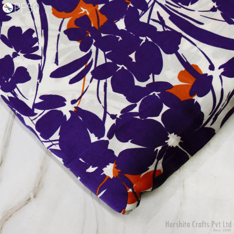 a close-up view of a fabric with a vibrant floral pattern in shades of purple and orange. The fabric appears to be a piece of cloth or textile, possibly used for clothing or home decor.