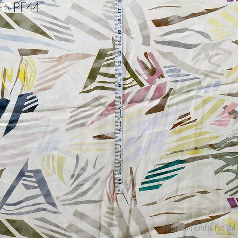 The image is a close-up of a fabric with a colorful abstract pattern, featuring various shapes and colors. There is a ruler visible in the image, which is likely used for measuring the fabric.
