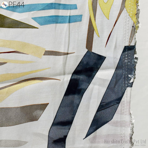 The image is a close-up of a fabric with a colorful abstract pattern, featuring various shades of blue, yellow, and brown.
