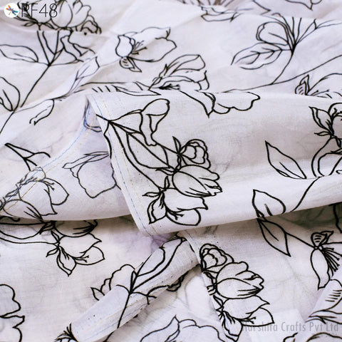 a close-up view of a fabric with a black and white floral pattern. The fabric appears to be a white material with black outlines of flowers and leaves, creating a visually striking contrast.