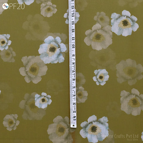 a close-up view of a fabric with a floral pattern, including white and green flowers. A ruler is placed vertically next to the fabric, providing a size reference.