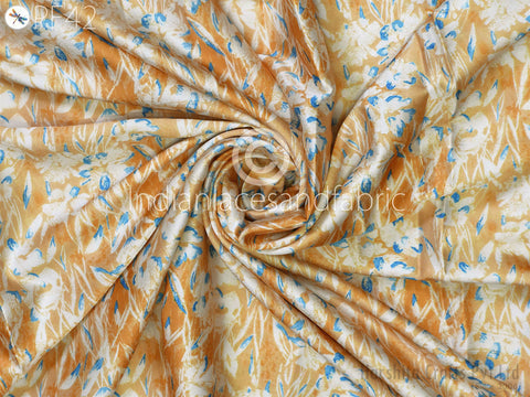 a close-up view of a fabric with a floral pattern in shades of orange and blue. The fabric appears to be crumpled and twisted, creating a sense of movement and texture.