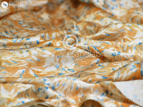 a close-up view of a fabric with a floral pattern in shades of orange and white. The fabric appears to be made of silk or a similar material, and the intricate design is visible.