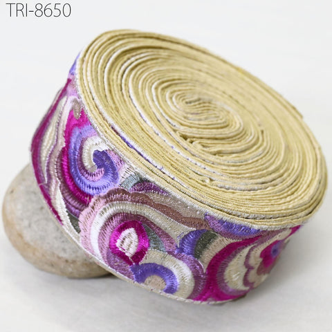 a decorative fabric with a spiral pattern in shades of pink, purple, and white. The fabric is rolled up and placed on a white surface.