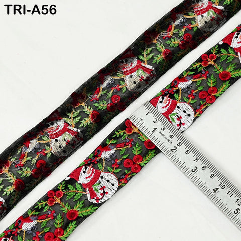 a close-up view of a decorative ribbon with a repeating pattern of snowmen and red berries. A ruler is placed next to the ribbon, indicating its size.