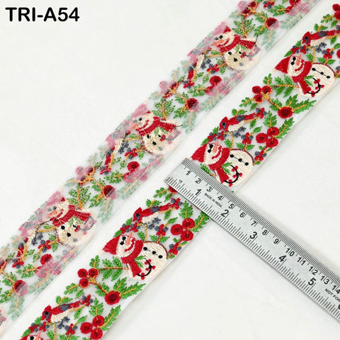 a decorative ribbon with a repeating pattern of snowmen and flowers. The ribbon is placed on a white surface, and a ruler is visible in the foreground, indicating the size of the ribbon.