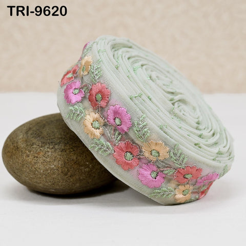 a decorative fabric with a floral pattern, including pink and orange flowers, placed on a white surface next to a rock.