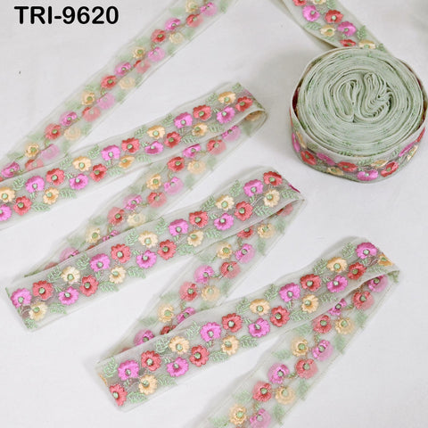 a collection of decorative fabric pieces with floral patterns, including a spool of green fabric with a similar floral design.