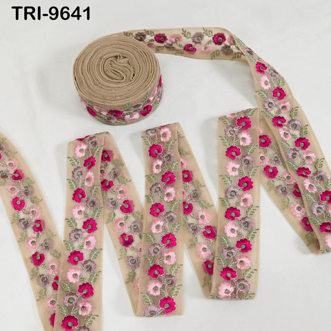 a collection of beige fabric with pink and green floral embroidery. The fabric appears to be a type of ribbon or decorative material, with the embroidery patterns visible on the surface.
