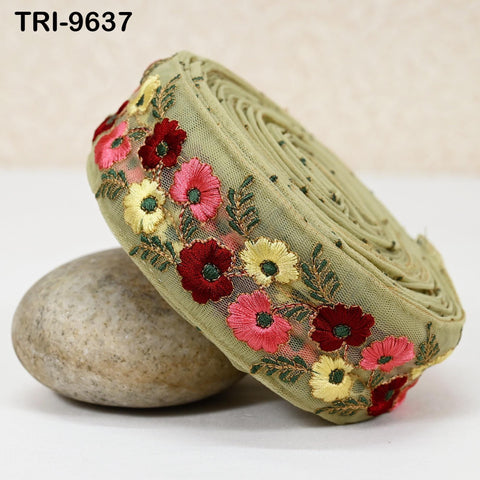 a green fabric with a floral design, including red, yellow, and pink flowers, and green leaves, placed on a white surface.