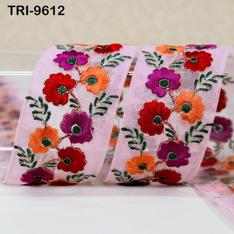 a close-up view of a pink fabric with a floral pattern of red, orange, and purple flowers, along with green leaves. The fabric appears to be a decorative piece, possibly used for sewing or crafting purposes.