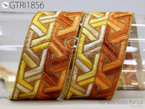 two ornate, decorative fabric pieces with a geometric pattern in shades of orange, yellow, and white. The pieces appear to be made of embroidered material and are displayed against a plain background.