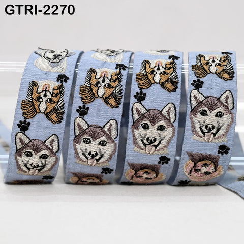 A collection of embroidered dog faces on a light blue fabric, with each dog's face and paw print pattern repeated across multiple panels.