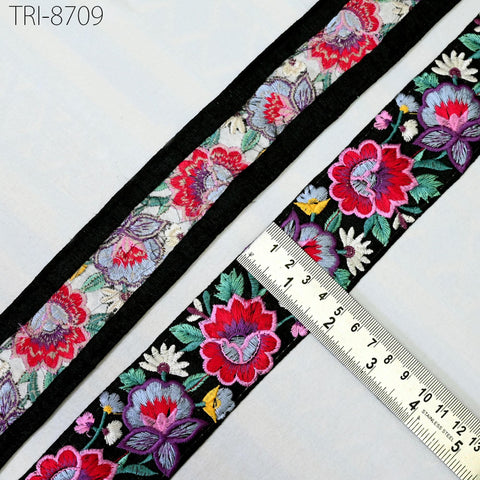 a close-up view of a decorative fabric with a floral pattern, featuring a black border and a ruler for size reference.