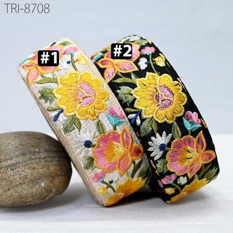 two colorful fabric pieces with floral embroidery, placed next to a rock.