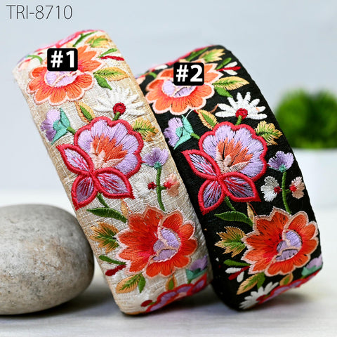 two colorful headbands with floral embroidery, placed next to each other on a surface.