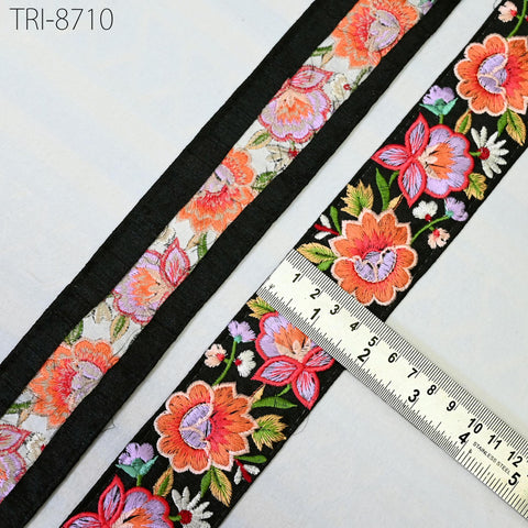 two spools of embroidered fabric with floral patterns, placed on a white surface. A ruler is placed next to the spools, indicating the size of the fabric.