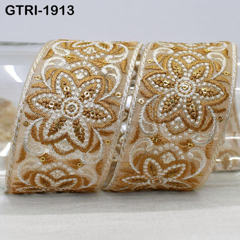 a decorative ribbon with intricate floral patterns in gold and white. The ribbon appears to be made of a shiny material and is displayed on a surface.