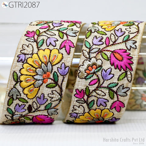 two decorative fabric pieces with a floral pattern, including yellow, pink, and purple flowers, as well as green leaves. The fabric appears to be made of a light-colored material, possibly cotton or linen, and is displayed against a white background.