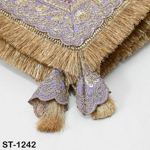 a close-up view of a decorative fabric with intricate embroidery and fringe details in shades of purple and gold.