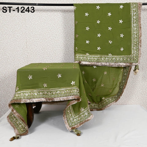 a green tablecloth with gold and white embroidered designs, hanging on a rack.