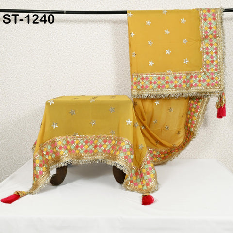a yellow and gold embroidered tablecloth with a floral pattern, hanging on a rack.