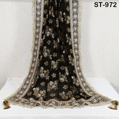 a black and gold embroidered fabric with a floral pattern, hanging on a white wall.