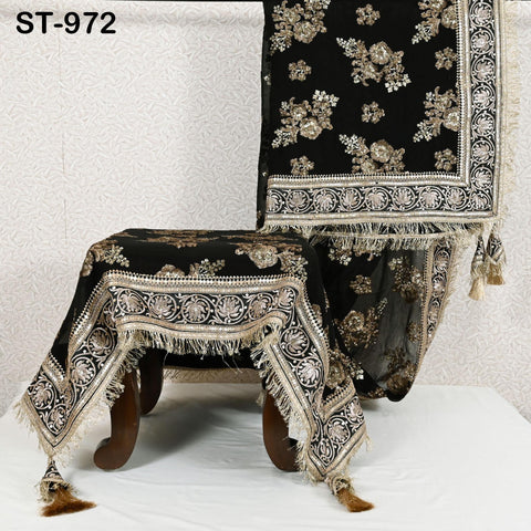 a black and gold table runner with a floral pattern, placed on a white surface.