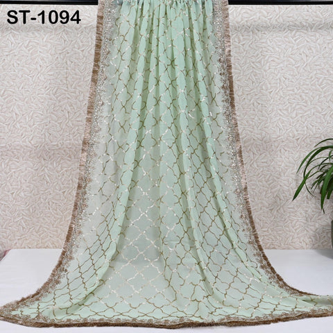 a long, mint green chiffon draped over a white surface, with a gold and white patterned border.