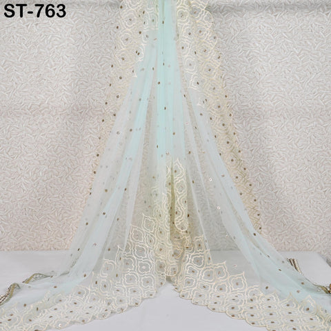 a long, flowing, sheer fabric with a delicate, gold-colored pattern. The fabric appears to be made of a sheer material, such as chiffon or tulle, and has a light blue color. The fabric is draped in a way that it cascades down, creating a sense of movement and elegance. The image does not contain any text or other discernible objects, and the focus is solely on the fabric and its intricate design.