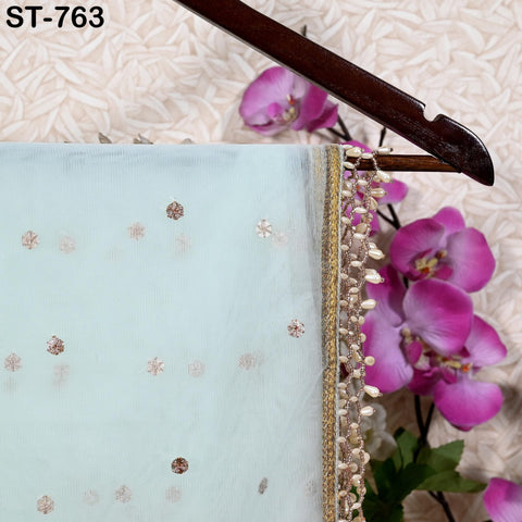 a light blue fabric with a gold and white embellished trim, hanging on a wooden hanger. The fabric has a delicate floral pattern, and the hanger is positioned against a background of pink orchids.