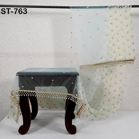 a black table with a white tablecloth and a decorative table runner with a floral pattern.