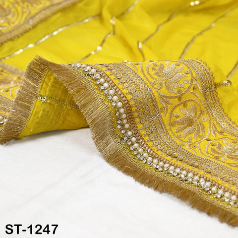 a close-up view of a yellow fabric with intricate gold embroidery and fringe details.